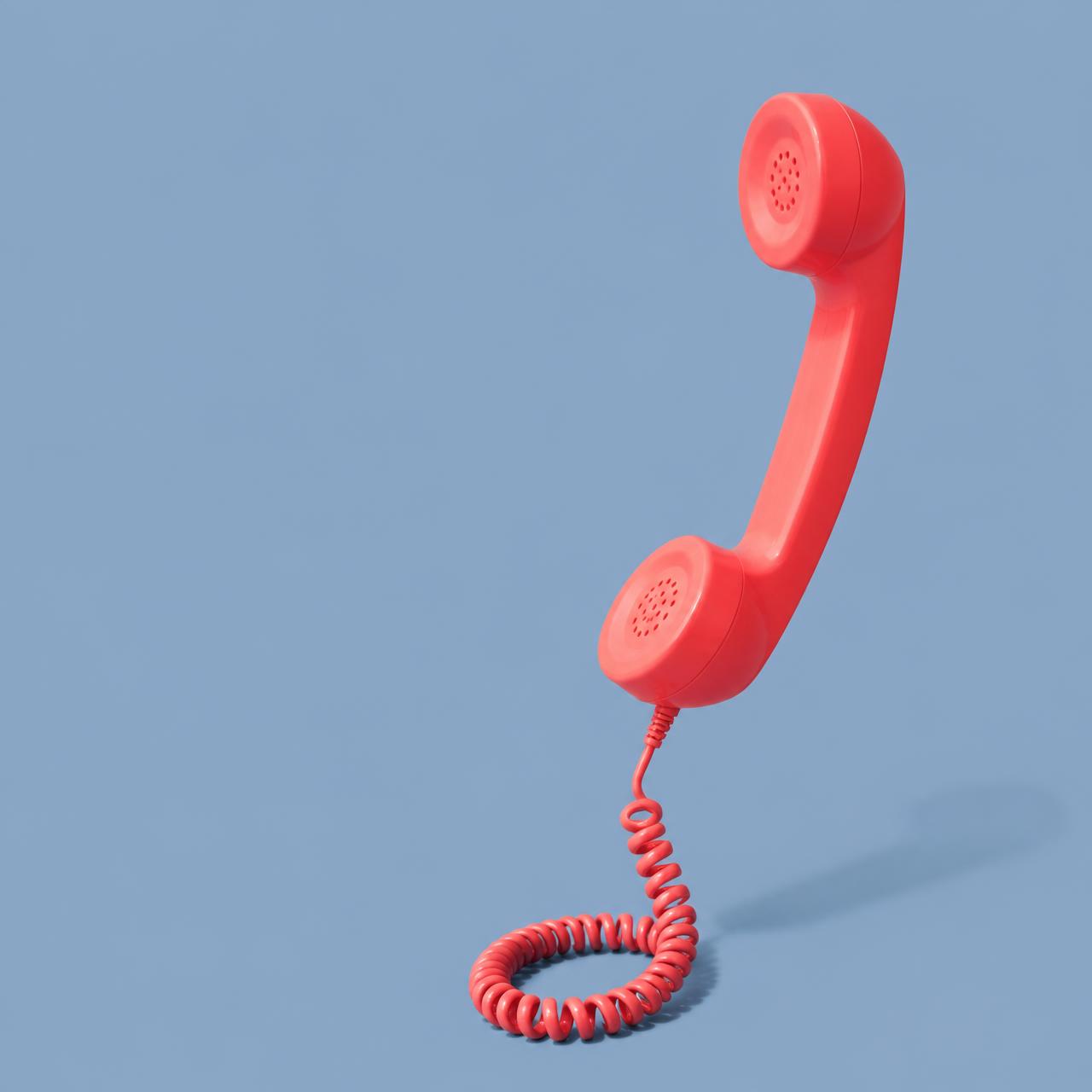 A coral retro telephone handset on a periwinkle background